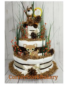 a three tiered cake decorated with pine cones and woodland animals