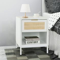 a white nightstand with a book on it next to a black and white checkered bed