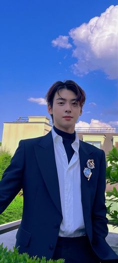 a young man in a suit and tie standing on a balcony with his arms out