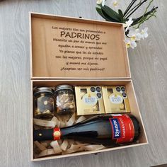 an open box with some wine and condiments in it on a table next to flowers