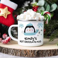 a mug filled with marshmallows sitting on top of a wooden table next to a christmas tree