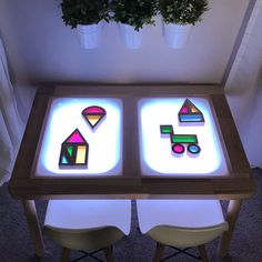 a table with some lights on it and two chairs around it in front of a potted plant