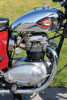 a red and black motorcycle parked on top of a road next to grass covered field