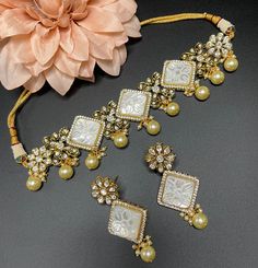 This elegant and gorgeous choker with matching earrings and is sure to be a hit for any event! The beautiful ivory color with gold pearls can match any outfit and the color is a gorgeous shade with a beautiful finish. White Tilla Choker For Wedding, White Kundan Lehenga With Stone Work, White Temple Jewelry Style Choker With Tilla, White Temple Jewelry Choker With Tilla, Bollywood White Jewelry Sets With Mirror Work, Festive White Jewelry Sets With Mirror Work, White Tilla Temple Jewelry Choker, Traditional Pearl Choker Necklace For Wedding, Wedding Temple Jewelry Pearl Choker Necklace