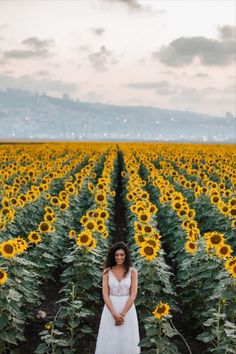 a woman standing in the middle of a sunflower field