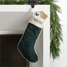 a green christmas stocking hanging from the side of a fireplace with a mom written on it