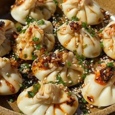 some dumplings are sitting in a bowl with sesame seeds on the side and garnished with green onions