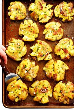 a pan filled with baked potatoes covered in cheese and seasoning next to a spoon