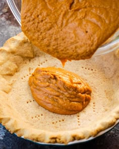 a pie crust is being poured with caramel sauce on top and an uncooked pumpkin pie crust in the middle