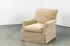 a beige chair sitting on top of a cement floor