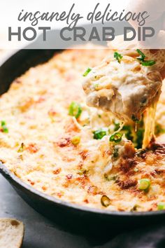 a person dipping some food into a skillet filled with cheese and green onions on the side