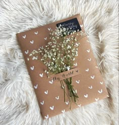 a brown book with white butterflies and flowers on it sitting on a furry surface next to a card