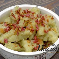 a white bowl filled with mashed potatoes and bacon on top of a wooden table