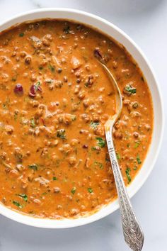 a white bowl filled with red lentula soup on top of a marble countertop