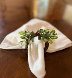 a napkin with some green leaves on it and a red berry sitting on top of it