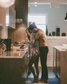 a man and woman standing in a kitchen next to each other with their arms around each other