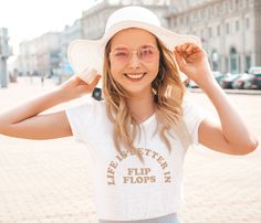 a woman wearing a white hat and glasses is standing in front of a brick road