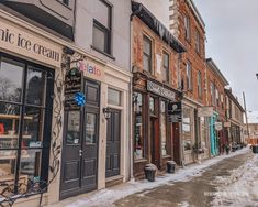 an old fashioned ice cream shop on the side of a snowy street in front of brick buildings