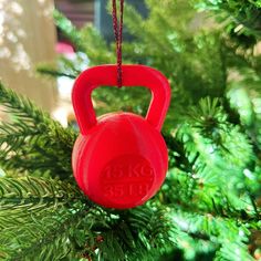 a red kettle ornament hanging from a christmas tree