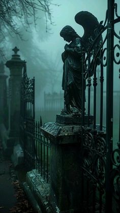 an angel statue sitting on top of a stone pillar next to a fence in the fog