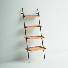 a wooden shelf with black metal legs and three shelves on each side, against a white wall