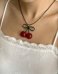 a woman wearing a necklace with two cherries attached to it