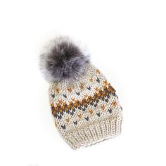 a knitted hat with a grey pom - pom on the top and an orange, white, and gray pattern