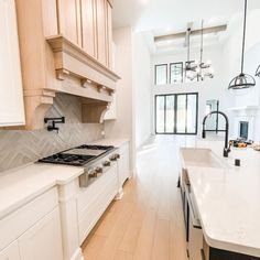 a large kitchen with white cabinets and wood flooring, along with an island in the middle