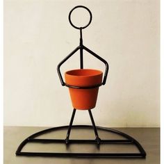 an orange pot sitting on top of a metal stand with a black base and legs