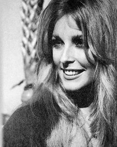 an old black and white photo of a woman with long hair smiling at the camera