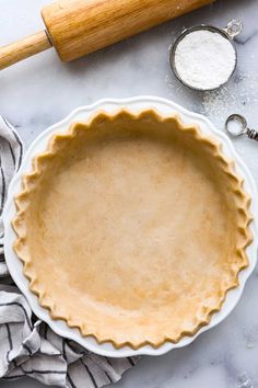 an uncooked pie crust in a bowl next to a rolling pin