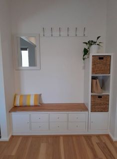 a room with white walls and wooden flooring next to a shelf filled with baskets