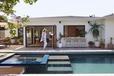 a woman walking into a house next to a swimming pool