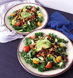 two plates filled with salad on top of a blue table cloth next to each other