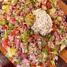 a wooden table topped with a salad covered in dressing