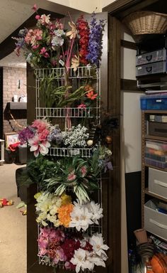 a bunch of flowers that are hanging on a wall next to a shelf with other items