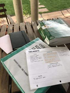 some books and papers on a wooden table outside with grass in the backround