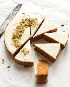 there is a cake with white frosting and nuts on it next to a knife