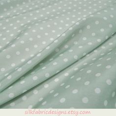 the fabric is very soft and has white polka dots on light green background, as well as in this photo