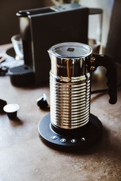 a metal coffee pot sitting on top of a table