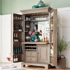 a wooden cabinet filled with lots of wine glasses and vases on top of it