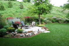 an outdoor patio with chairs and flowers in the back yard, surrounded by lush green grass