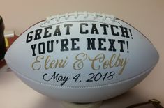 a football with the words great catch you're next engraved on it sitting on a table