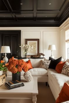 a living room with white couches and orange pillows on the coffee table in front of it