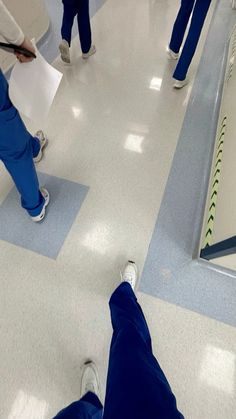 several people in scrub suits are walking down the hall with their feet on the floor