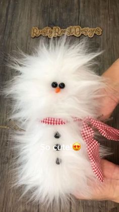 a hand holding a white fluffy snowman ornament