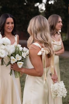 bridesmaids in long dresses holding bouquets and looking at each other with smiles on their faces