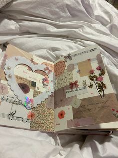 an open book sitting on top of a bed covered in white sheets and paper flowers