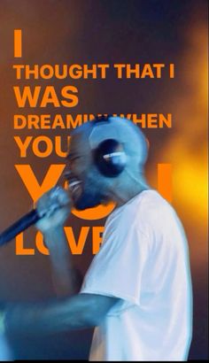 a man with a mask on holding a microphone in front of a sign that says i thought that i was dreaming when you love him