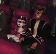 two people are sitting in the middle of an empty auditorium with purple seats and one person is wearing sunglasses